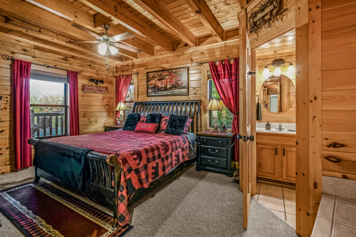 A warm, inviting bedroom with a bed adorned with decorative throw pillows, wooden ceiling and walls, and red curtains. A vanity area with a mirror is visible, enhancing the sense of personal space and privacy. The room feels restful and private, echoing the peace and thoughtful details described in the section.